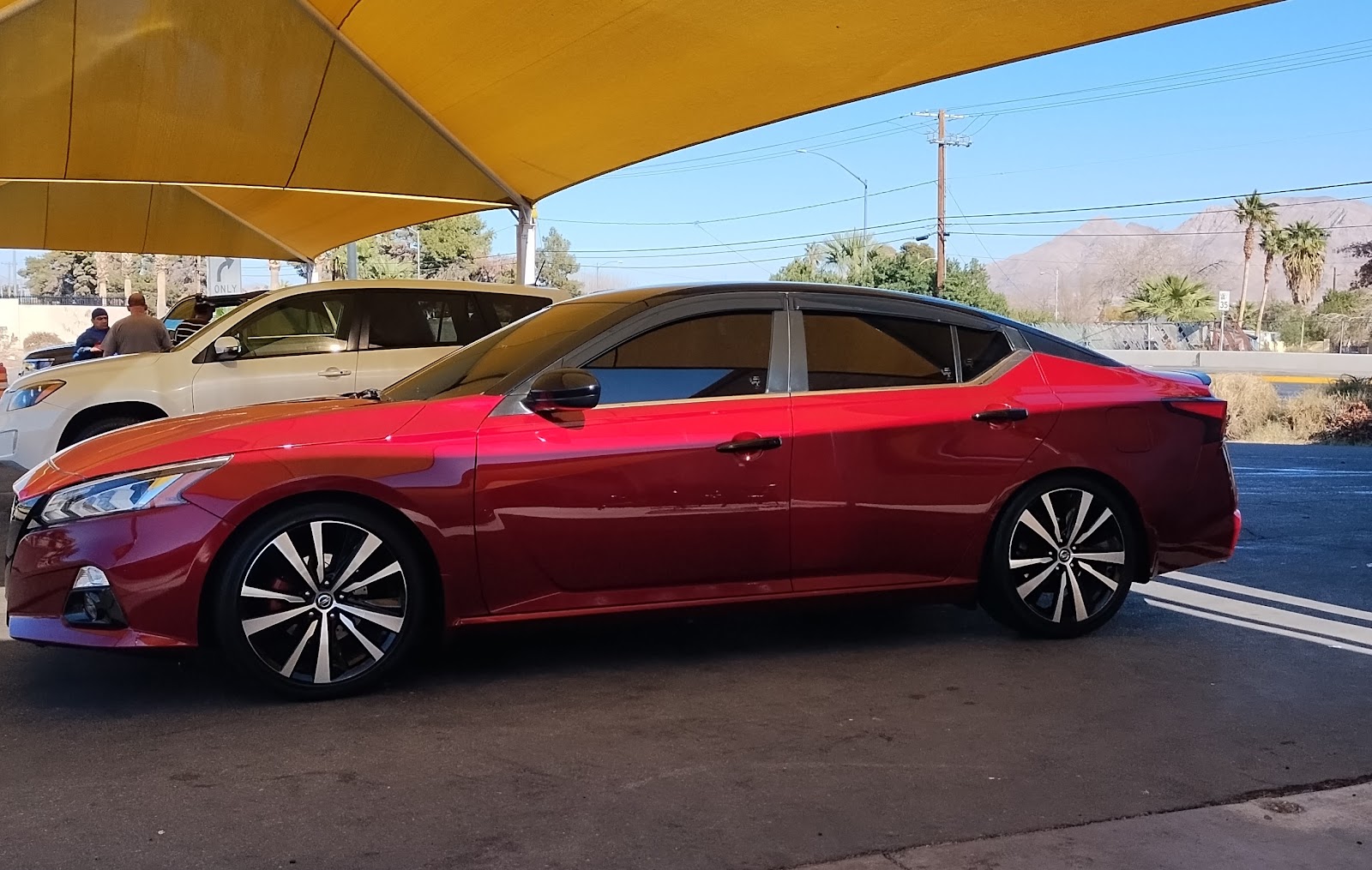 Side profile of a clean red Nissan Altima under the car wash canopy