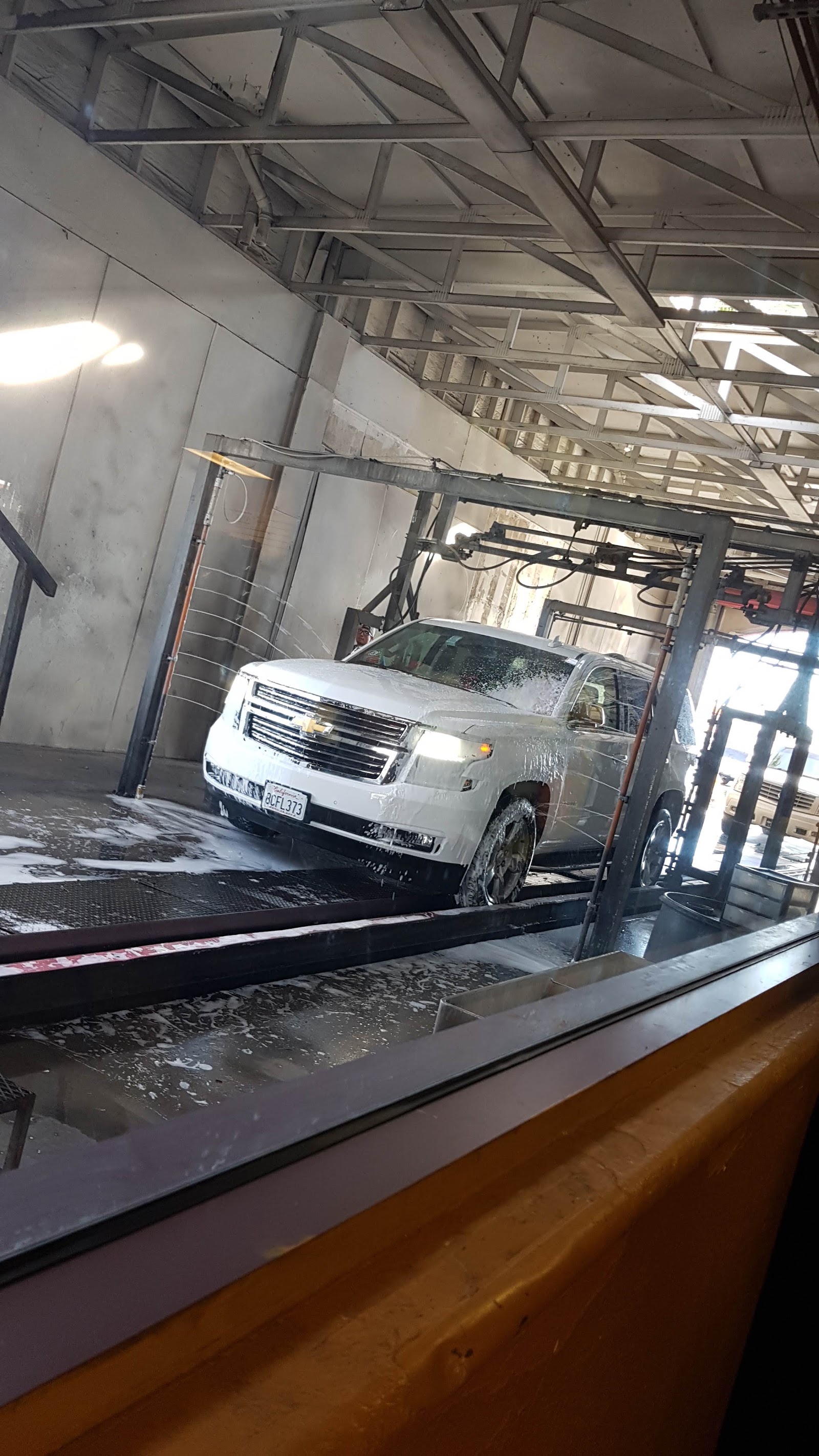 White Chevrolet SUV covered in soap inside the car wash
